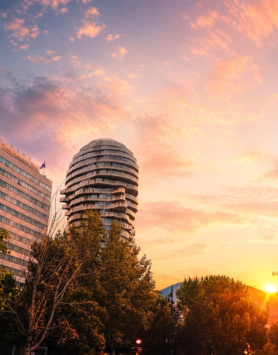 Modern round residential tower next to the Tirana International Hotel at sunset