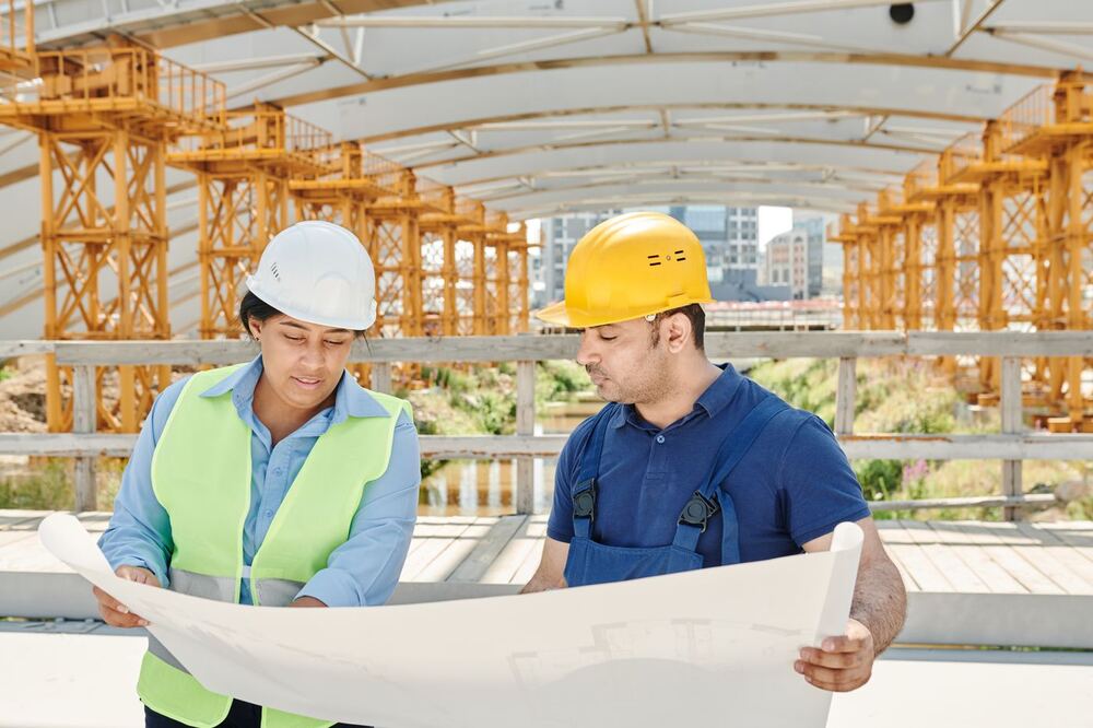 Two site engineers reviewing project plans together
